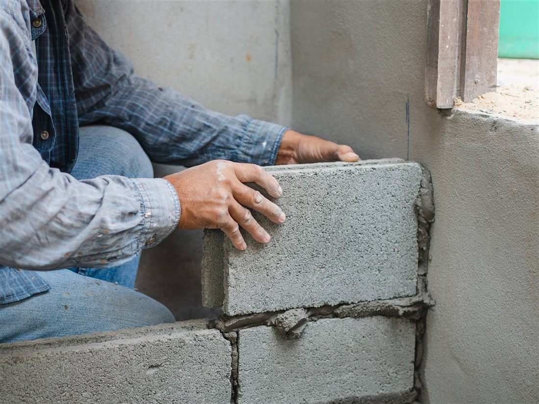 Pedreiro assentando bloco de concreto em uma parede